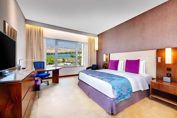 A hotel room with a bed, desk, chair, and a television. - Crowne Plaza Muscat Ocec (Muscat)