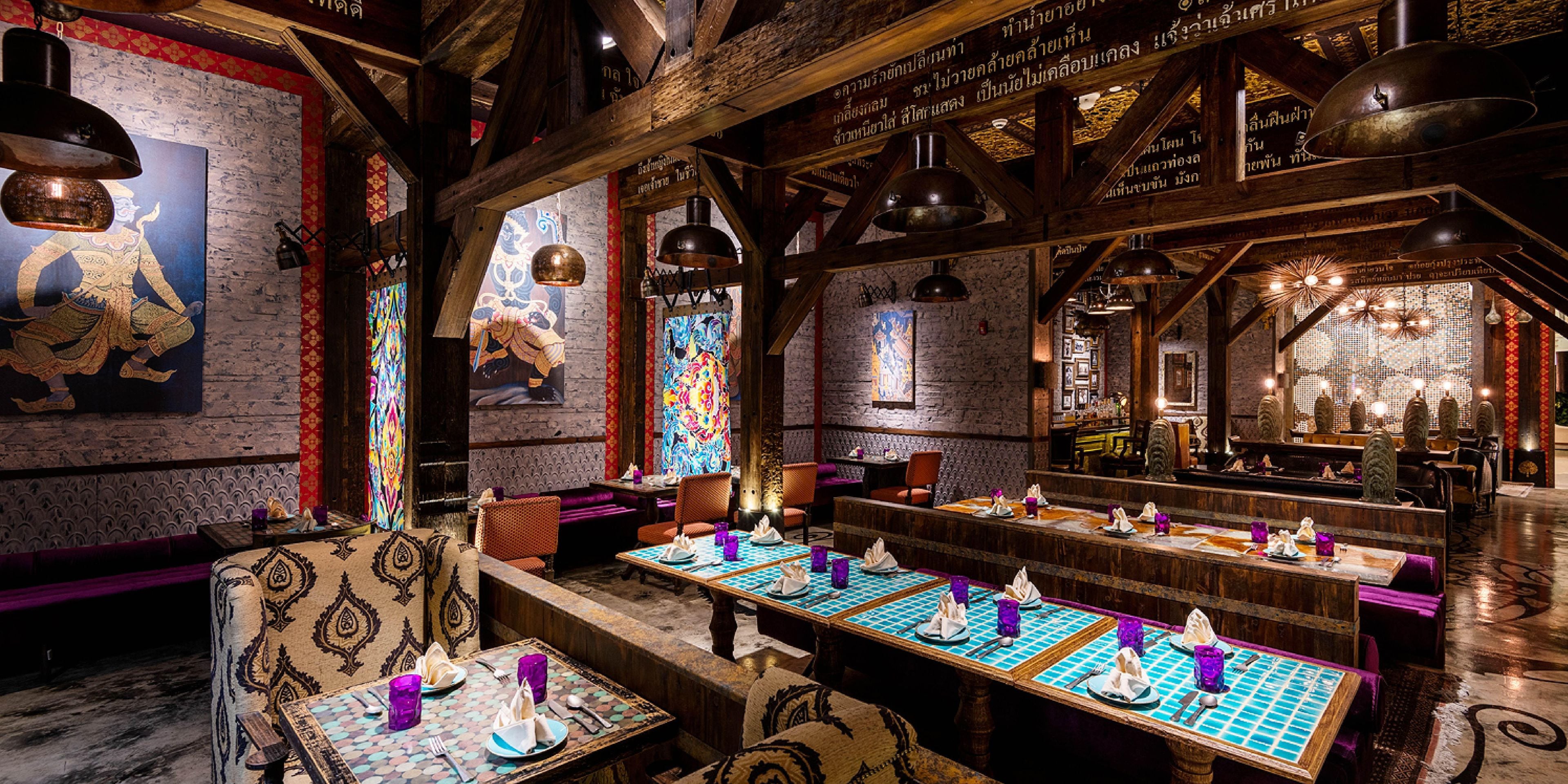 A restaurant with wooden beams, patterned walls, and tables set for dining.