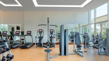 Un gimnasio con cintas de correr, máquinas de pesas y pesas sueltas.