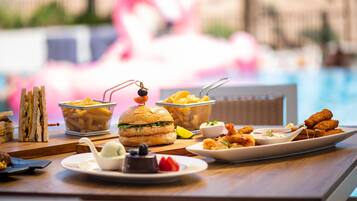 Una mesa de comedor con diversos alimentos, como sándwiches, hamburguesas y aperitivos fritos.