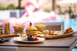 A dining table with various food items, including sandwiches, burgers, and fried snacks. - Crowne Plaza Muscat Ocec (Muscat)