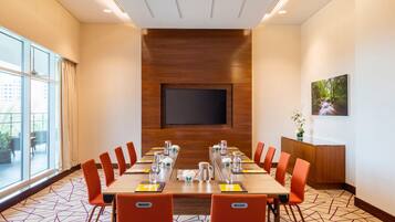 A conference room with a large table, chairs, a TV, and a window.