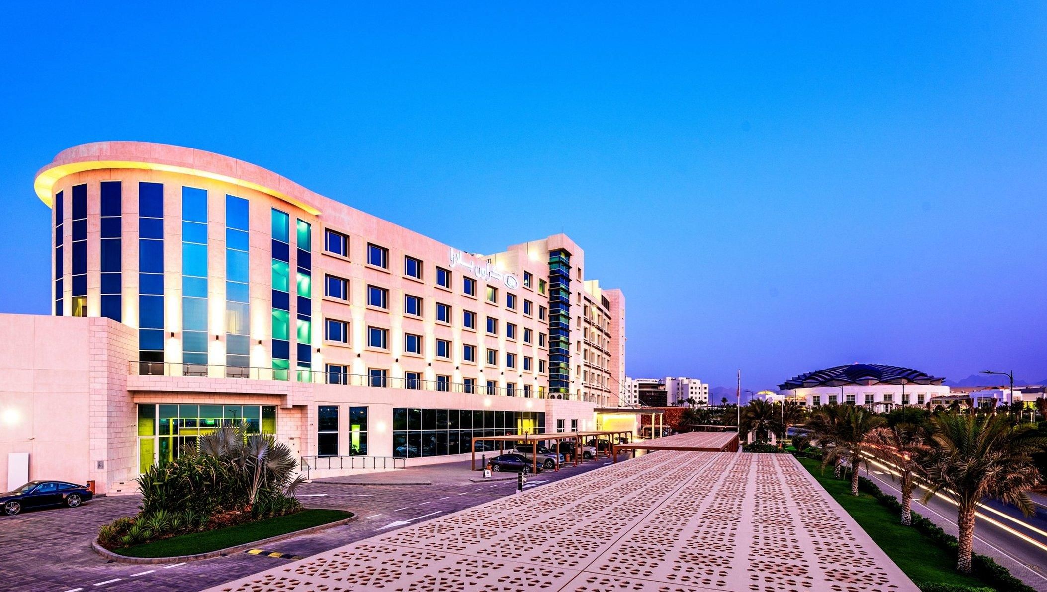 A multi-story hotel with a curved facade, large windows, and a covered outdoor area.