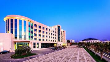 A multi-story hotel with a curved facade, large windows, and a covered outdoor area.
