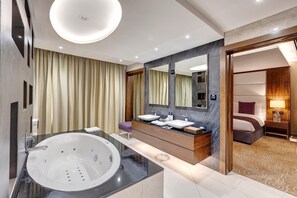 A modern hotel bathroom with a large bathtub, two sinks, a vanity, and a mirror. - Crowne Plaza Muscat Ocec (Muscat)