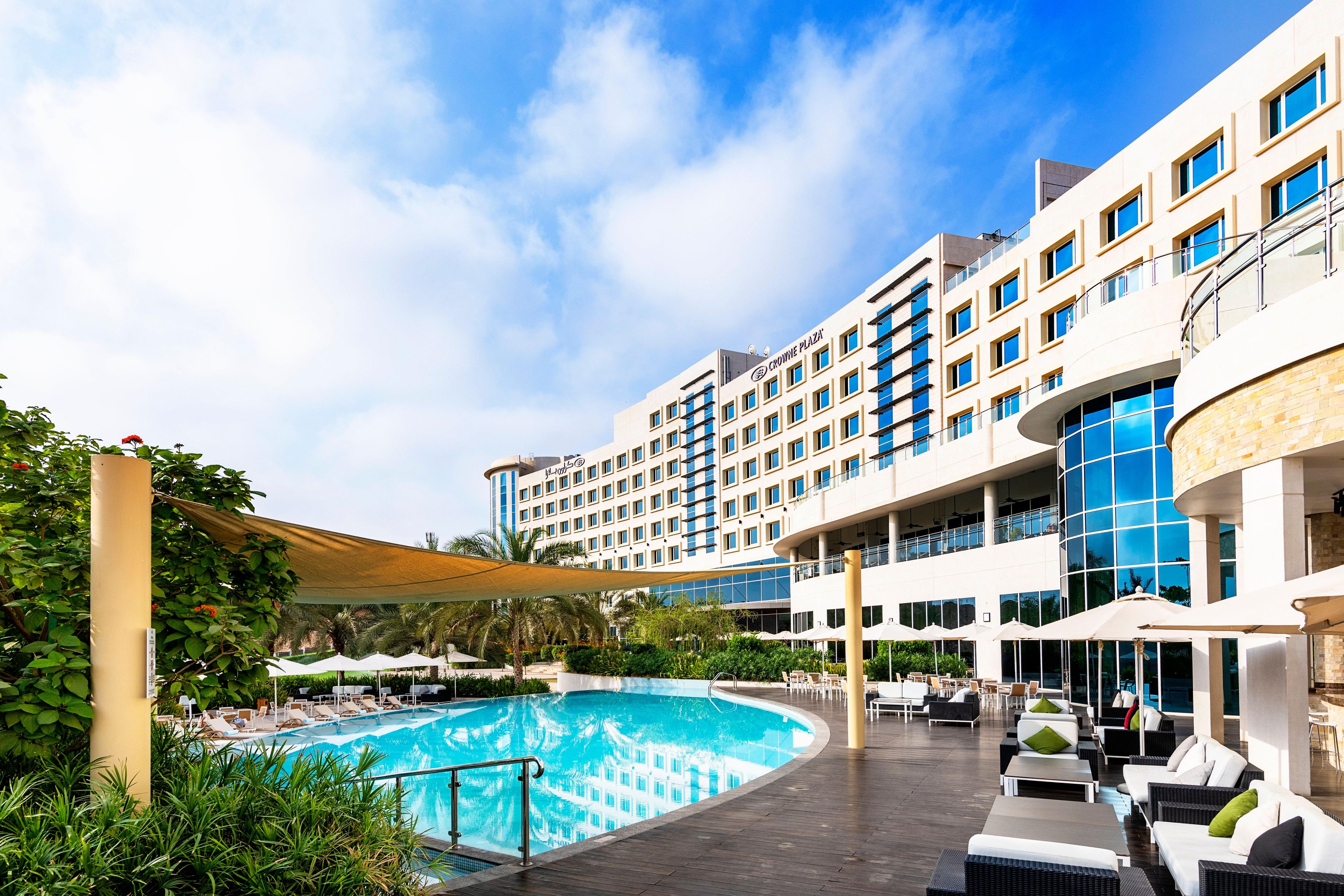 Um hotel com piscina, área de estar externa e um edifício grande com vários andares.