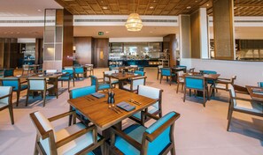 A restaurant with wooden tables and blue chairs, a bar area, and a ceiling with wooden beams. - Crowne Plaza Muscat Ocec (Muscat)