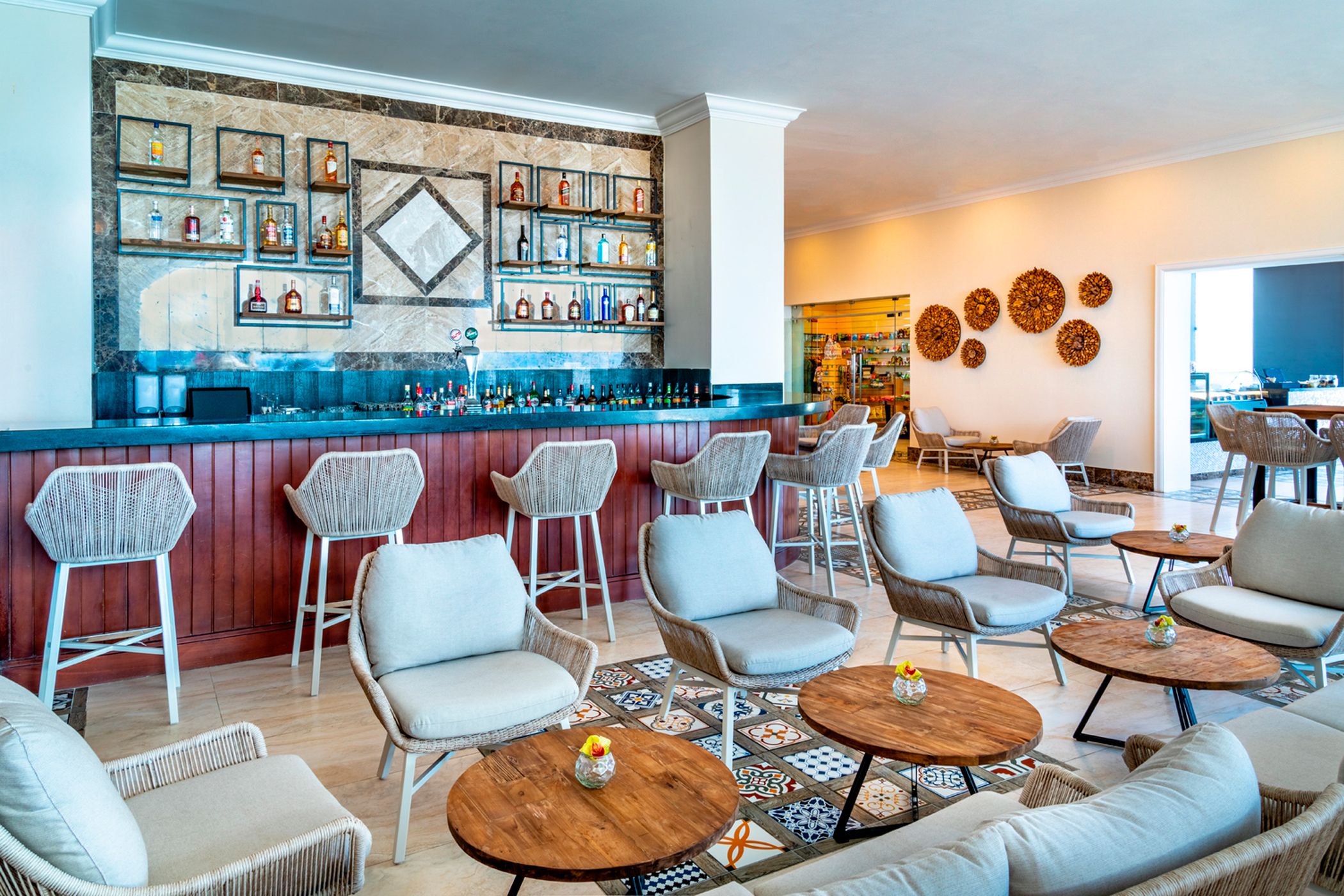 A bar area with wicker chairs, a counter with bottles, and a patterned floor.