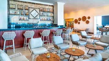 A bar area with wicker chairs, a counter with bottles, and a patterned floor.