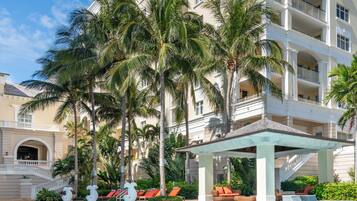 A hotel with a pool, palm trees, and a multi-story building.