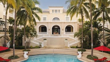 A pool area with a clear view of a building with multiple balconies and a central entrance.