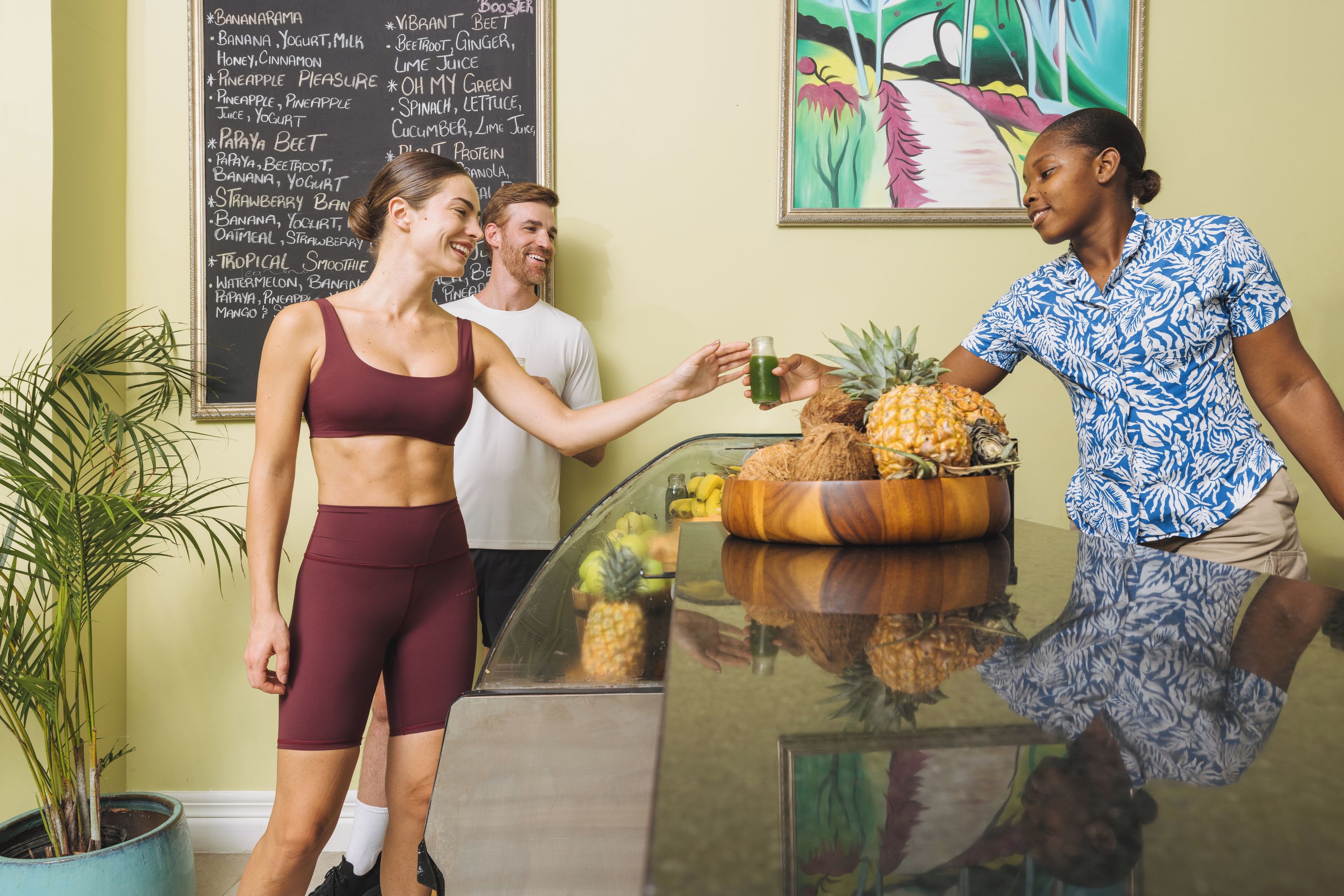A reception area with a glass counter, a potted plant, and a chalkboard menu listing various food and drink items.