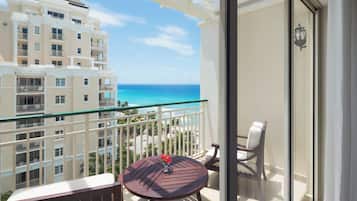 A balcony with a view of the ocean and a building in the background.