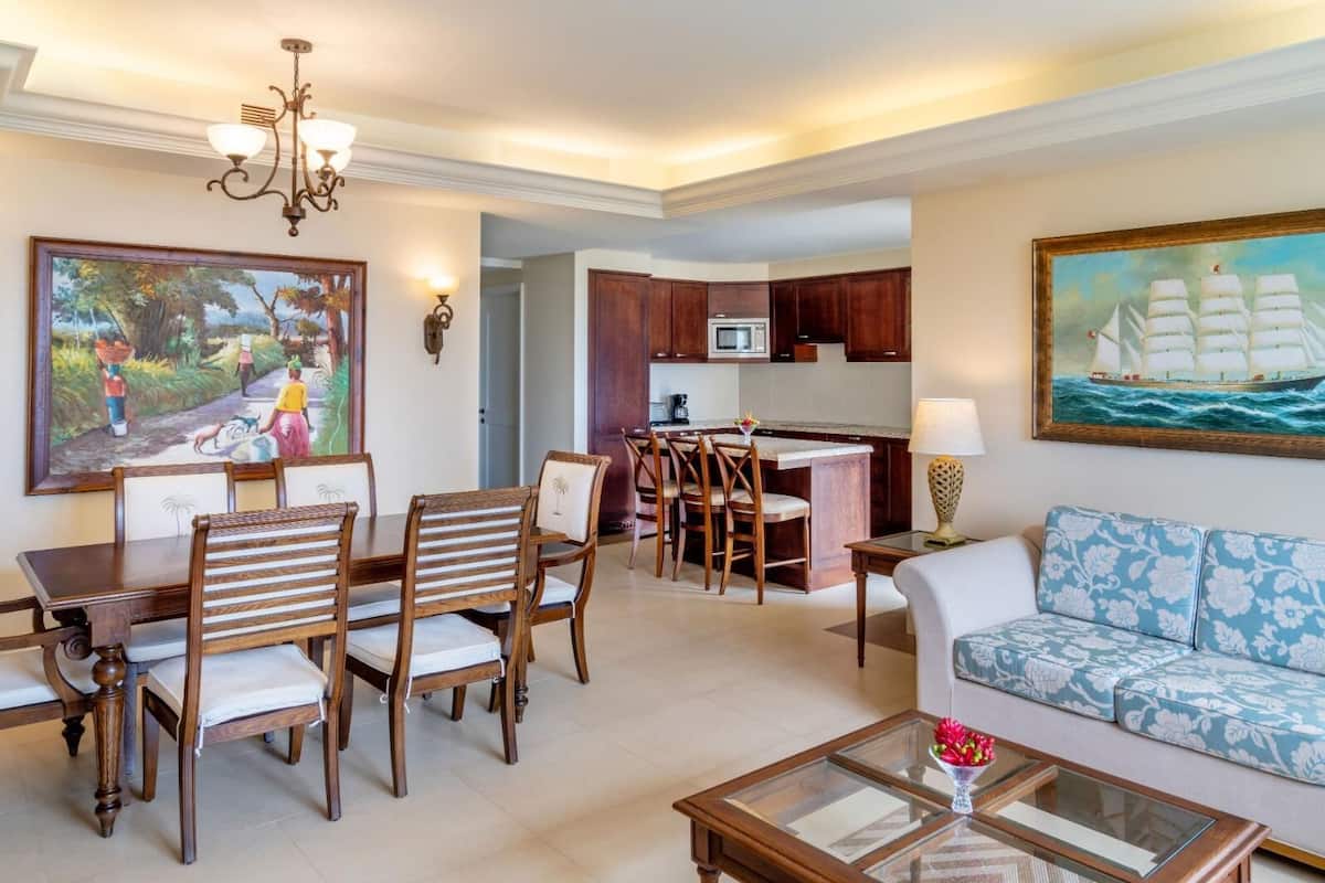 Amplia sala de estar con una mesa de comedor, sillas, un sofá y una cocina al fondo.