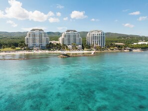Un resort con tres edificios de gran altura, una playa y aguas turquesas cristalinas.