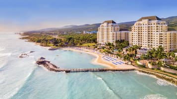A coastal hotel with multiple buildings, a beach, and a pier.