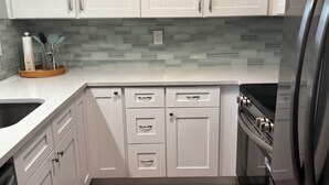 A kitchen with white cabinets, a stainless steel refrigerator, and a tiled backsplash. - SEA you soon! Totally refreshed from top to bottom! January 2027 available! (Indian Shores)