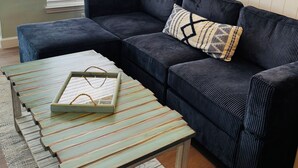 A living room with a sectional sofa, a coffee table, a lamp, and framed artwork on the wall. - SEA you soon! Totally refreshed from top to bottom! January 2027 available! (Indian Shores)
