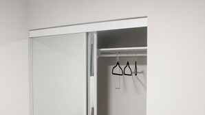 Et værelse med skab med skydedør, en loftlampe og en stikkontakt på væggen.