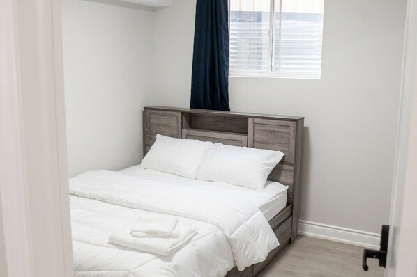 Une chambre à coucher avec un lit, une fenêtre avec des rideaux et une porte.