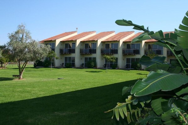 A multi-story building with a consistent roofline, balconies, and a well-maintained lawn. - Pastoral Hotel (HaGalil HaElyon)