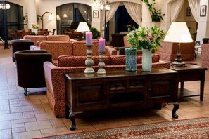 A lobby with patterned sofas, a wooden coffee table, and decorative vases. - Pastoral Hotel (HaGalil HaElyon)