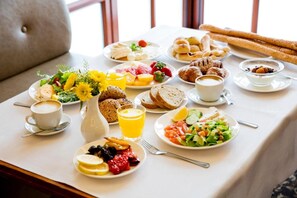 A breakfast table with various food items, including bread, pastries, fruits, and a coffee cup. - Pastoral Hotel (HaGalil HaElyon)