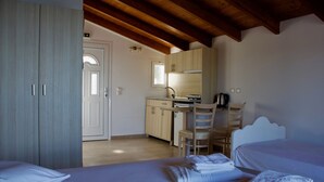 Una habitación con cama, escritorio y kitchenette.