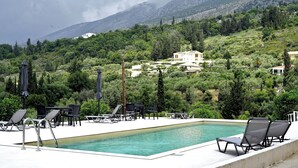 Zona de piscina con sillones reclinables y vistas a un paisaje montañoso.