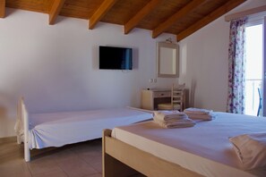 A bedroom with two beds, a TV, a mirror, and a desk. - Agios Gerasimos (Kefalonia)