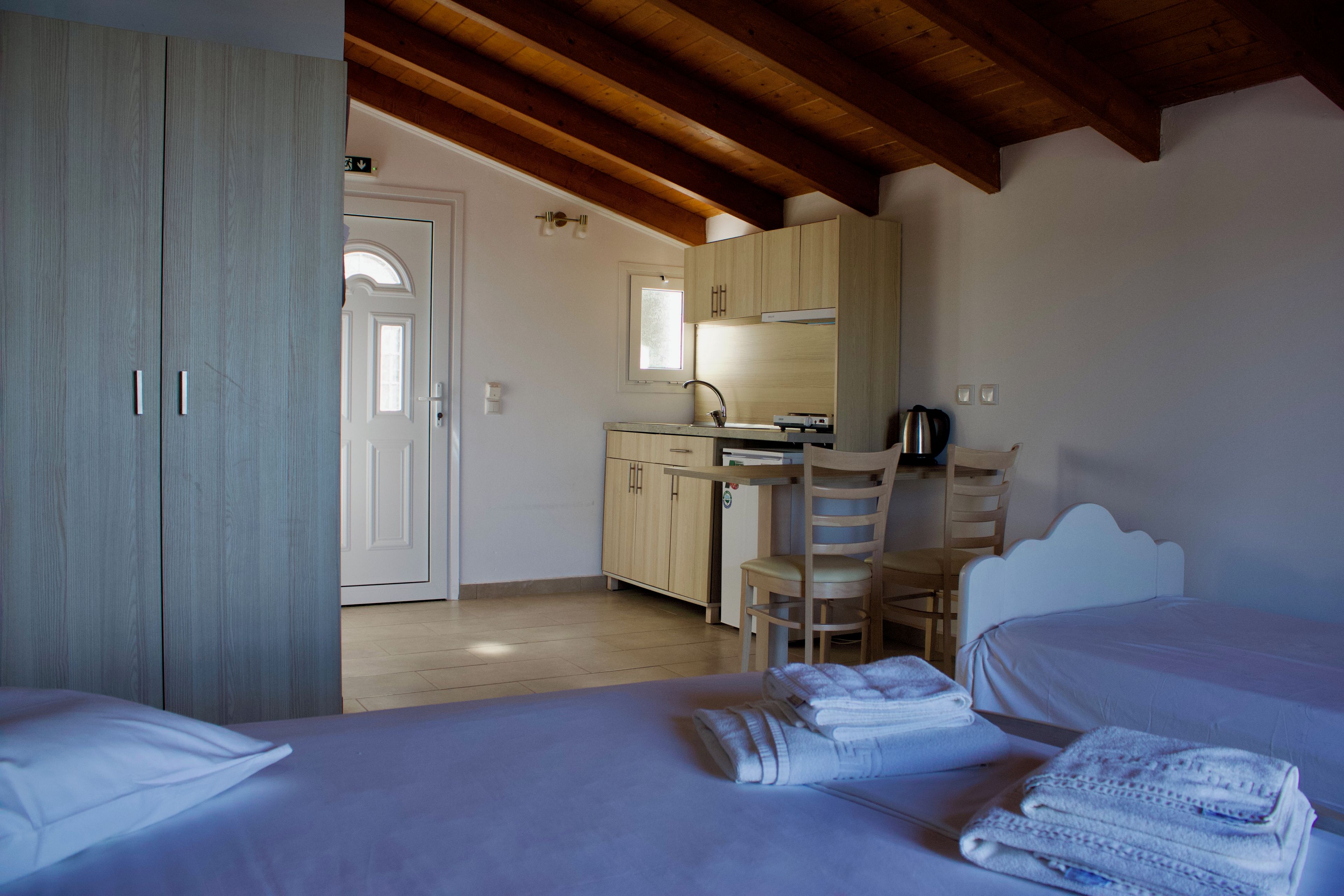 A room with a bed, a desk, and a kitchenette.