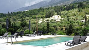 Área de piscina com espreguiçadeiras e vista para uma paisagem montanhosa.