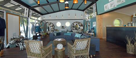 Una habitación amplia con techo azul, muebles de mimbre y una mesa redonda.