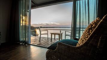 Una habitación con una silla de mimbre, una pequeña mesa y vistas al mar a través de amplios ventanales.