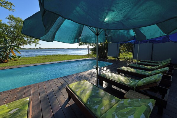 A poolside area with lounge chairs and a large umbrella.