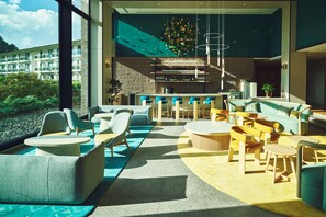 A modern lounge area with seating, a bar, and a view of the building's exterior. - ANA Holiday Inn Resort Karuizawa by IHG (Naganohara)