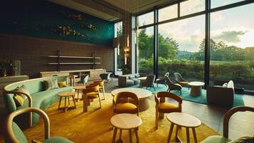 A modern interior with a curved sofa, round wooden tables, and a view of greenery outside.