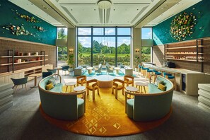 A modern library with a central seating area, bookshelves, and large windows offering a view of the outdoors. - ANA Holiday Inn Resort Karuizawa by IHG (Naganohara)