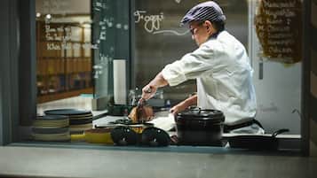 A chef preparing food in a kitchen with a chalkboard menu in the background.