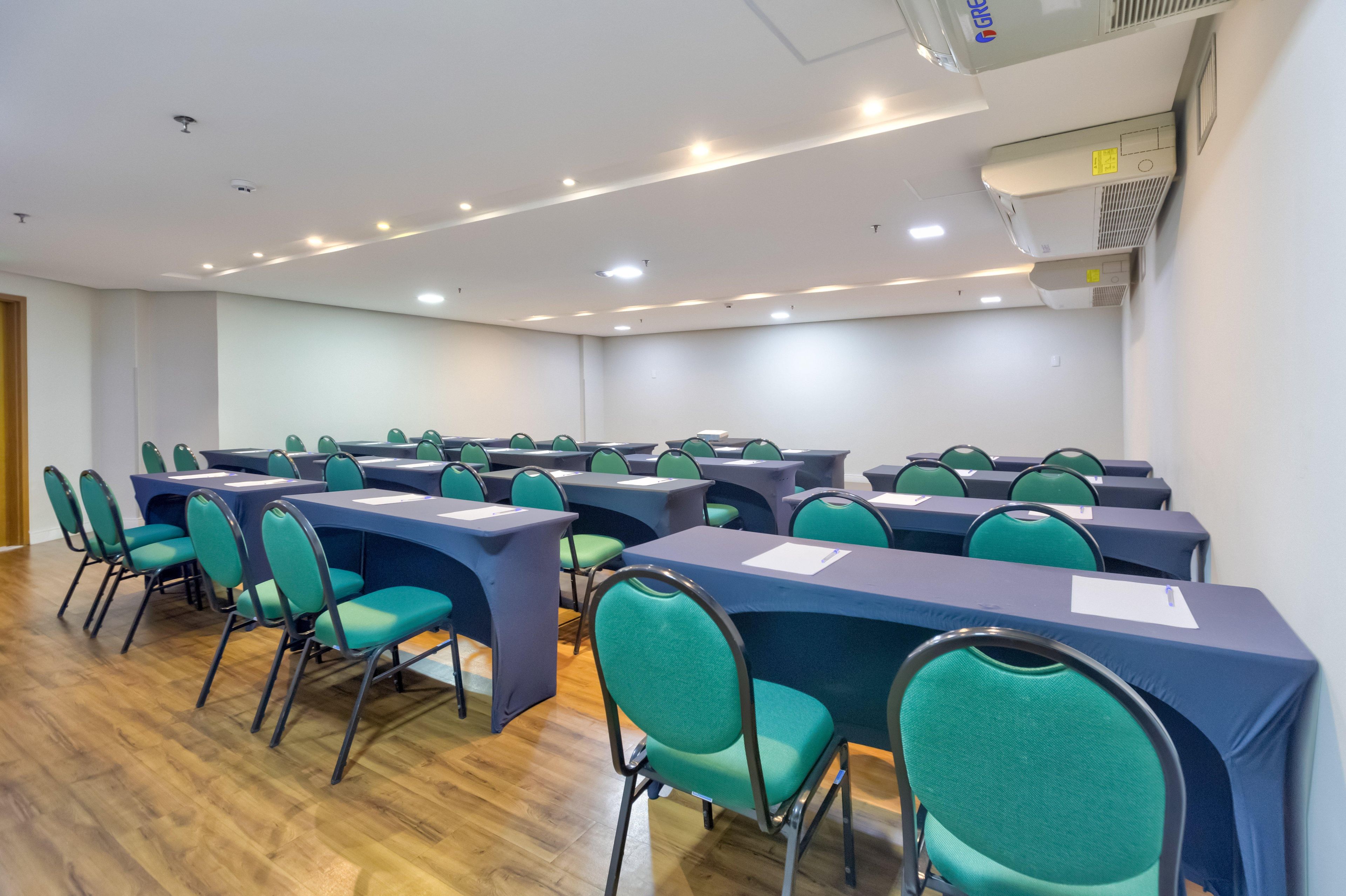 Una sala de conferencias con mesas y sillas, luces en el techo y un equipo de aire acondicionado.
