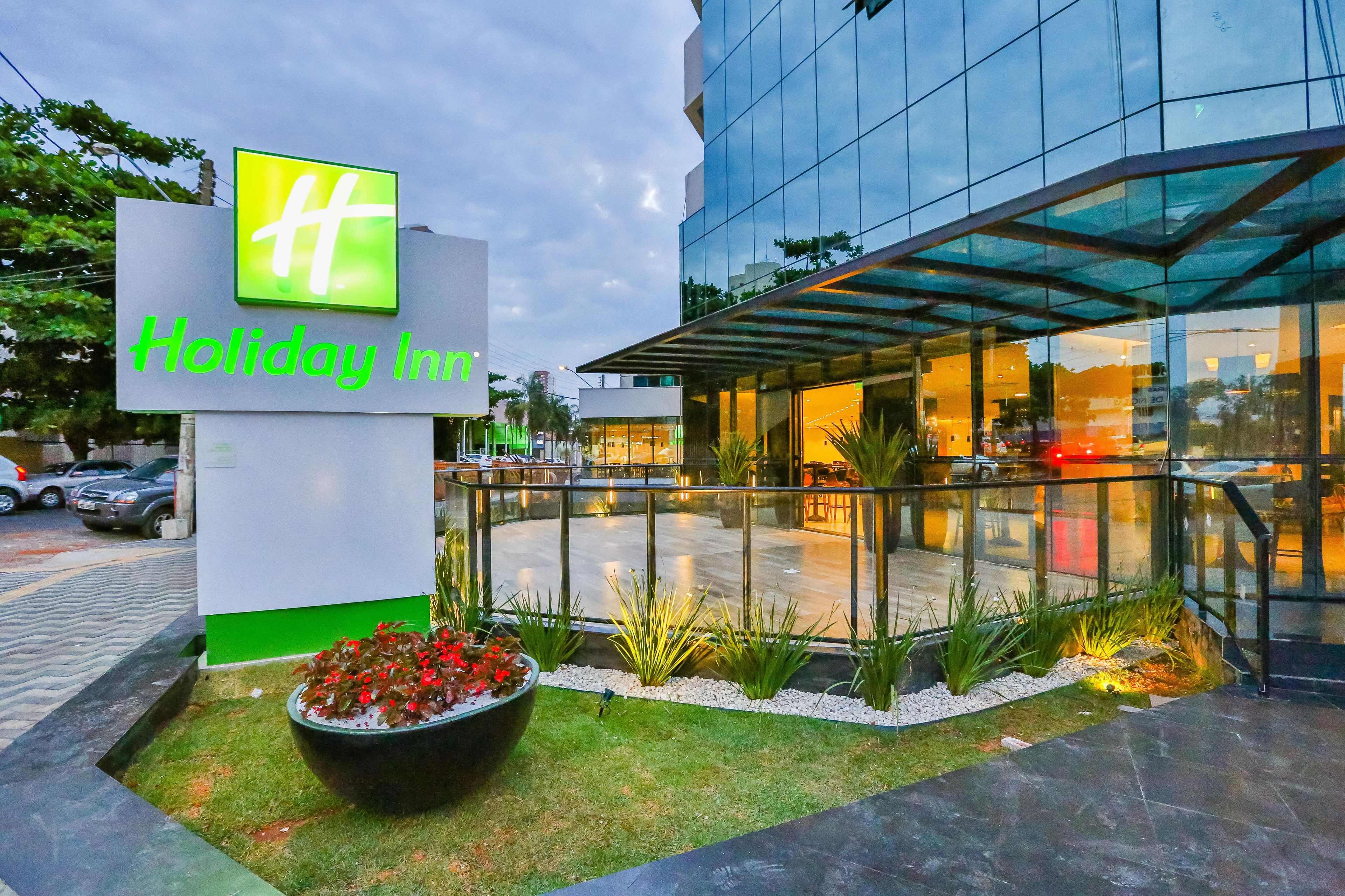 A Holiday Inn sign with a modern glass building in the background.