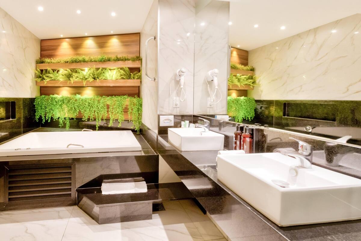 Un baño moderno con una bañera grande, dos lavamanos y un espejo.