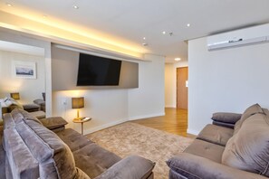 En moderne stue med et fladskærms-TV, sofaer, en lampe og trægulv.