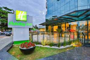 Ein Holiday Inn Schild vor einem modernen Glasgebäude.