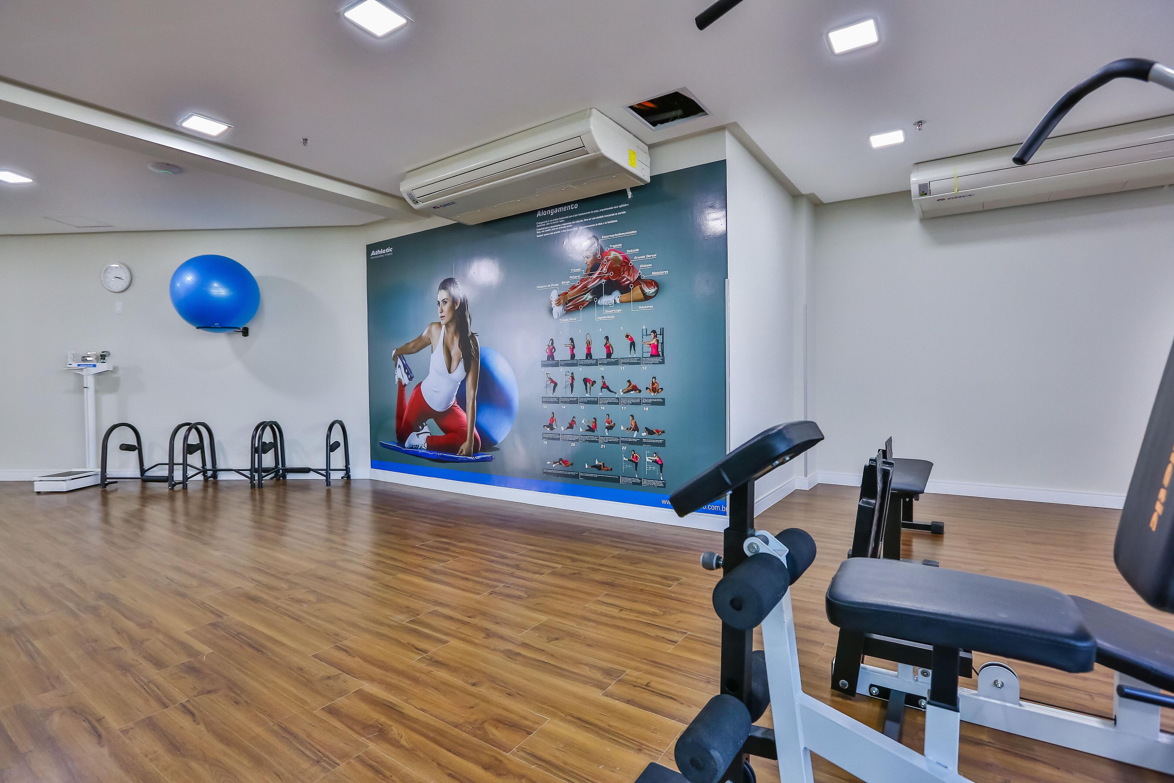 A gym with exercise equipment, a blue exercise ball, and a poster on the wall.