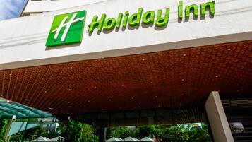 A Holiday Inn hotel with a prominent green logo, a modern facade, and a covered entrance area.