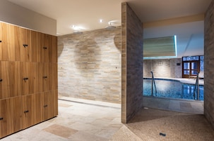 A modern bathroom with a stone wall, a wooden cabinet, and a pool area.