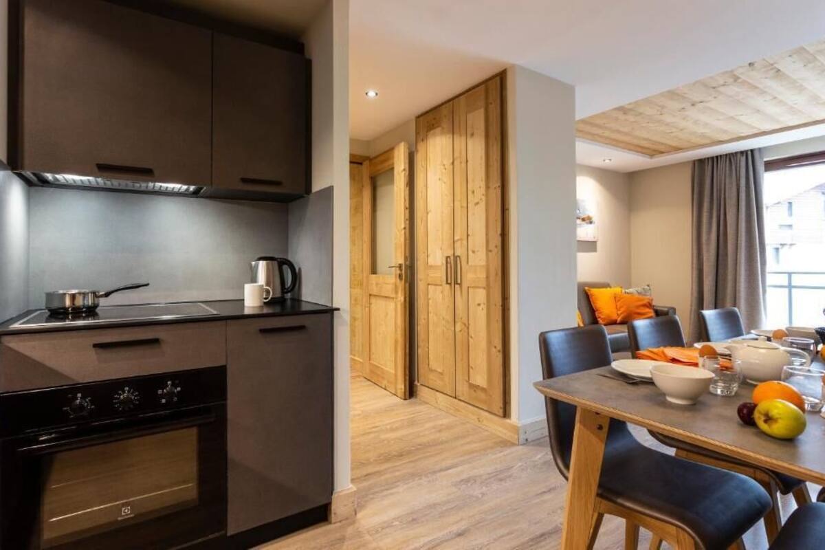A modern kitchen with dark cabinetry, a stove, and a dining area with a table set for two.