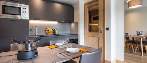 A modern kitchen with a built-in microwave, a stove, and a dining area with a table set for two.