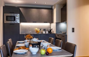 A modern kitchen with a built-in microwave, a coffee machine, and a fruit bowl on the counter. - Residence Daria-i Nor (Huez)